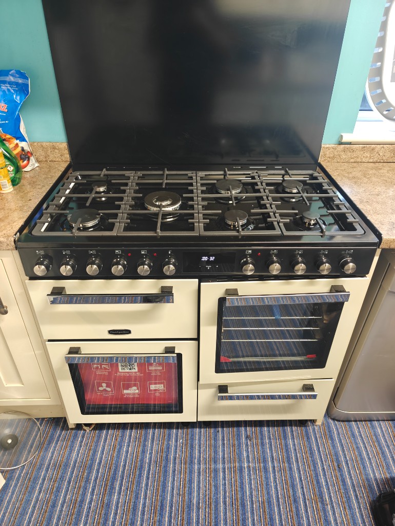 Cream Montpellier range cooker with black splashback installed in kitchen