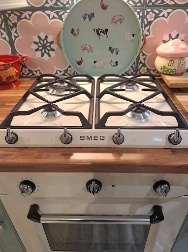Cream Smeg gas hob and built-in oven installed in a timber worktop kitchen