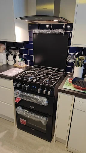 New black freestanding gas range with stainless steel Hotpoint chimney hood
