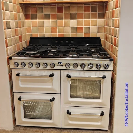Cream Smeg range cooker fitted in a mosaic-tiled alcove