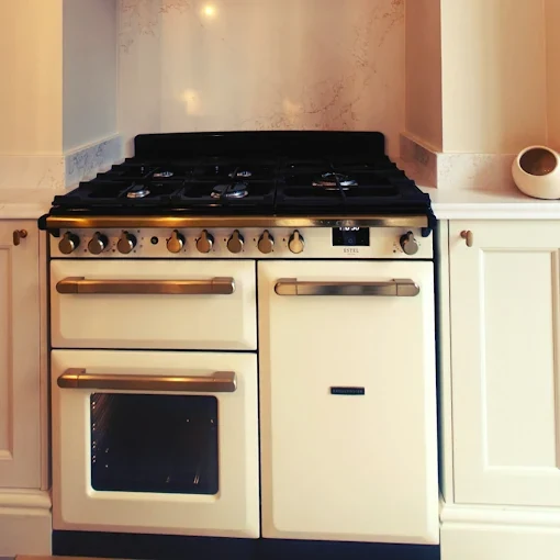 Cream Rangemaster range cooker with stone splashback and matching cabinetry